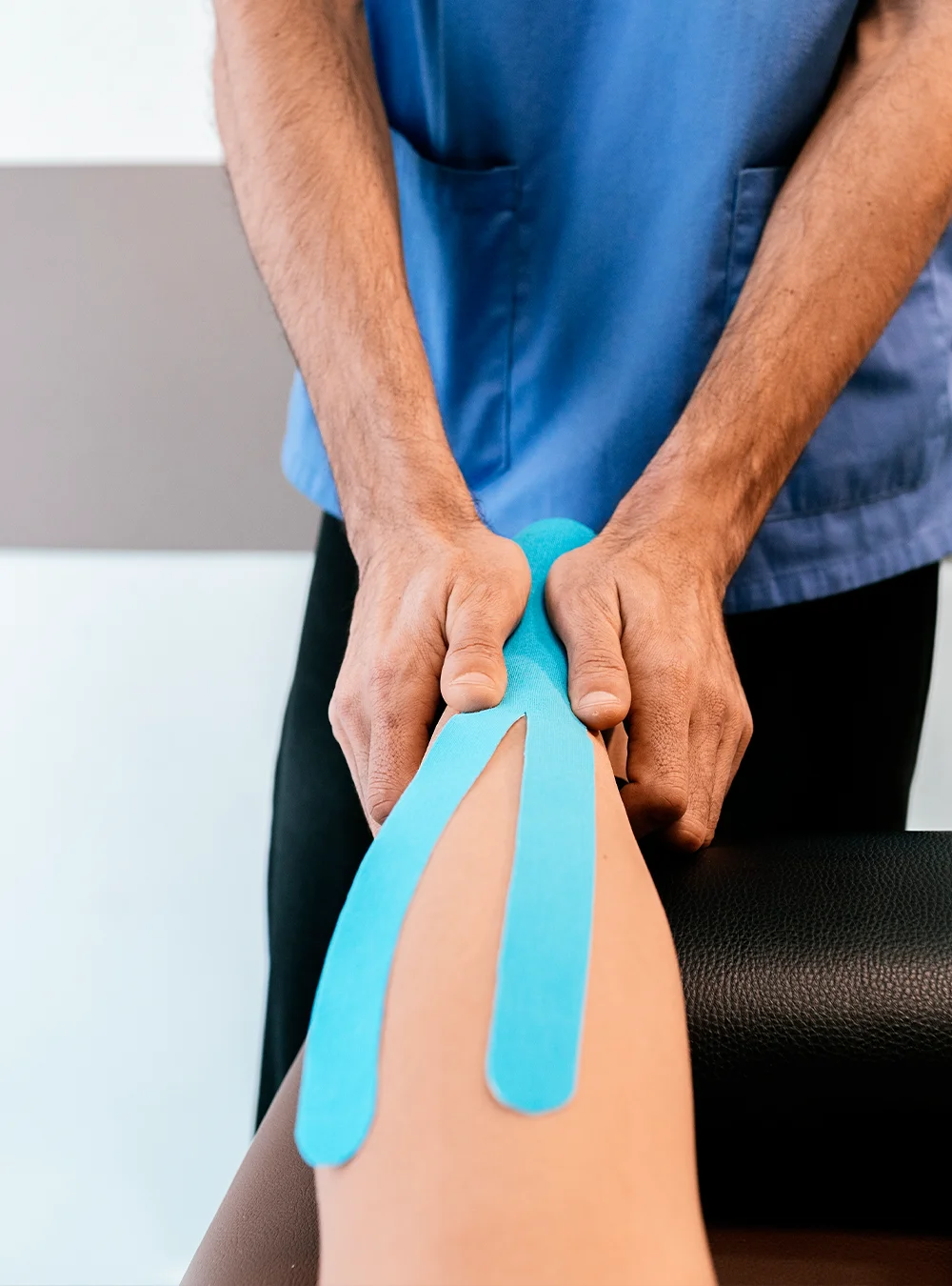 Blue kinesiology tape being applied to a knee Blue kinesiology tape being applied to a knee