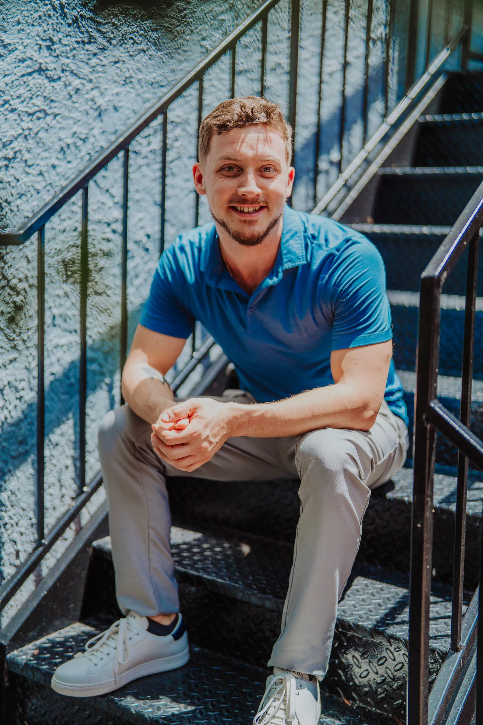 Dr. Jarod Ward sitting on outdoor steps in a blue polo